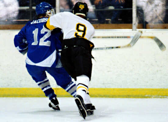 Lee Allen takes a Trinity Trojan into the boards.
